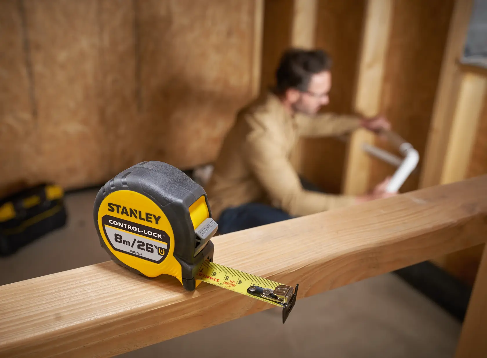 STANLEY STHT37236-5 tape measure with yellow and black casing on wooden beam, close-up photography.
