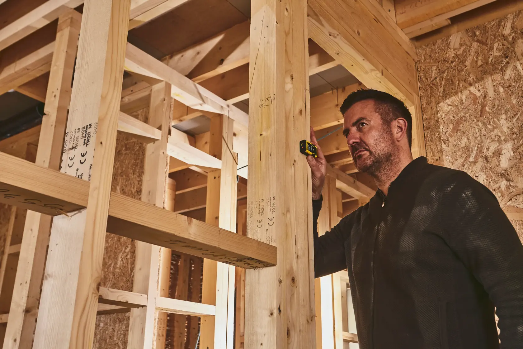 STANLEY STHT77666-0 laser distance measurer in use during wall framing construction.