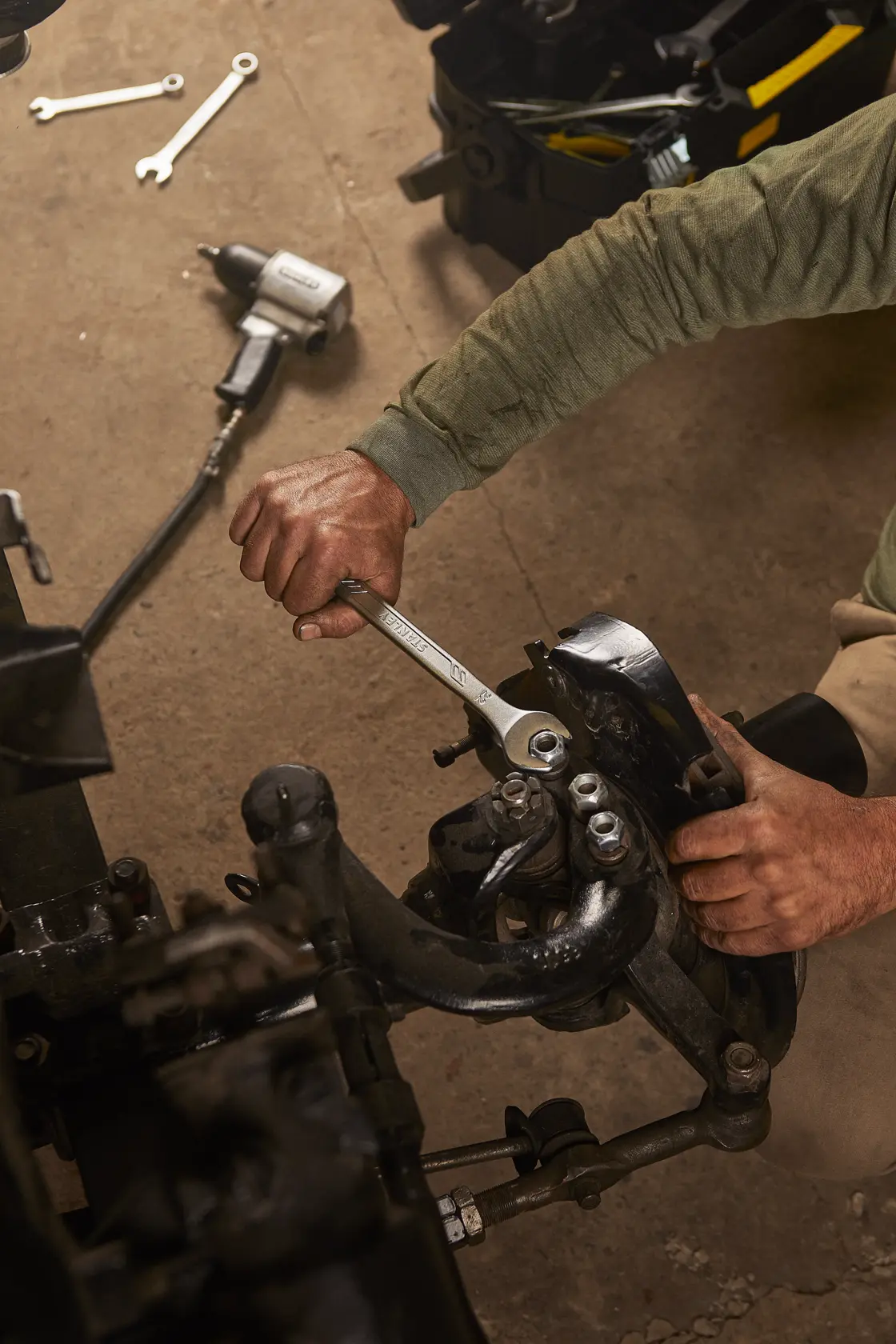 STANLEY STMT72819 wrench in use on automotive part in workshop setting, overhead angle.