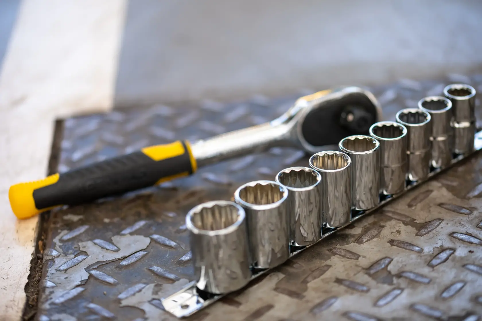 STANLEY STMT82671-0 ratchet wrench with black and yellow handle and socket set on metal surface, side angle.