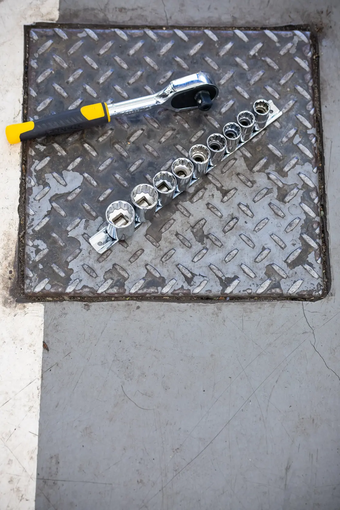 STANLEY STMT82671-0 socket wrench set with yellow and black handle and chrome sockets on metal surface, top view.