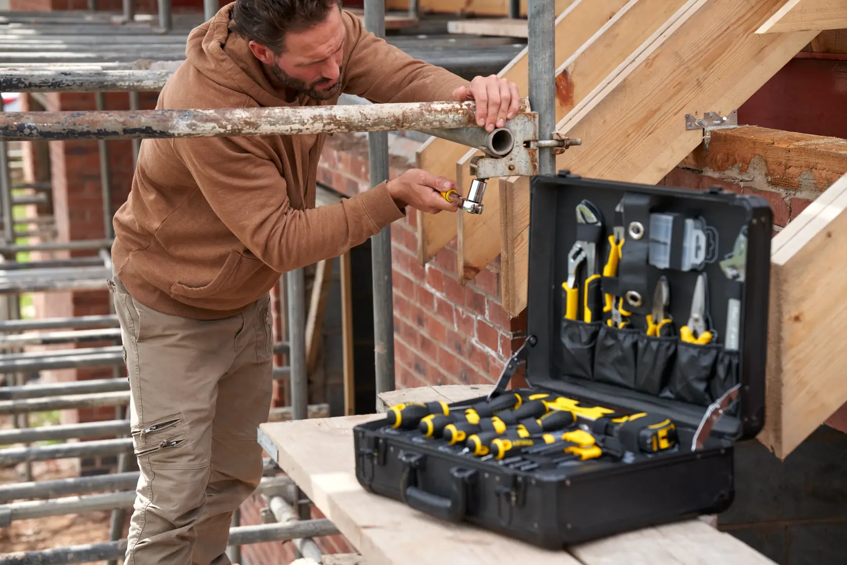 STANLEY STMT98109-1 maintenance suitcase with 142 PCS tools open on site, used by worker assembling scaffold.
