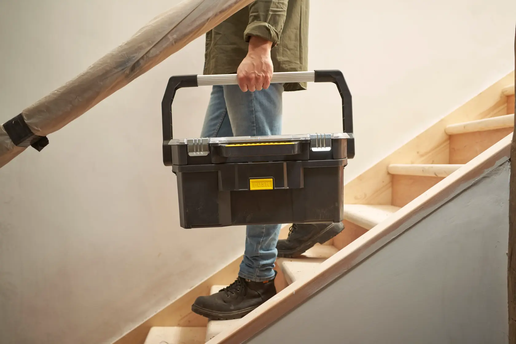STANLEY STST1-70317 black toolbox with silver handle being carried up stairs, product photography.