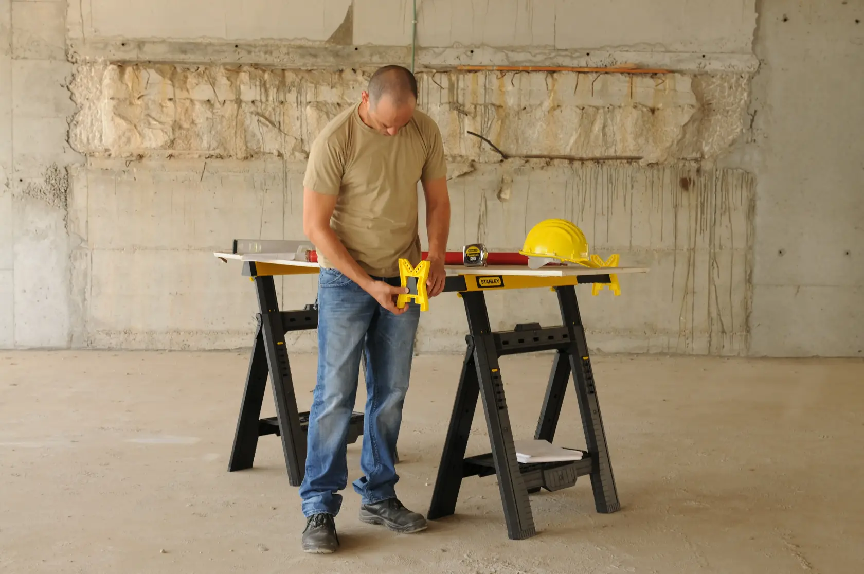 STANLEY STST1-70559 photography of folding sawhorse used for construction with tools and safety helmet.