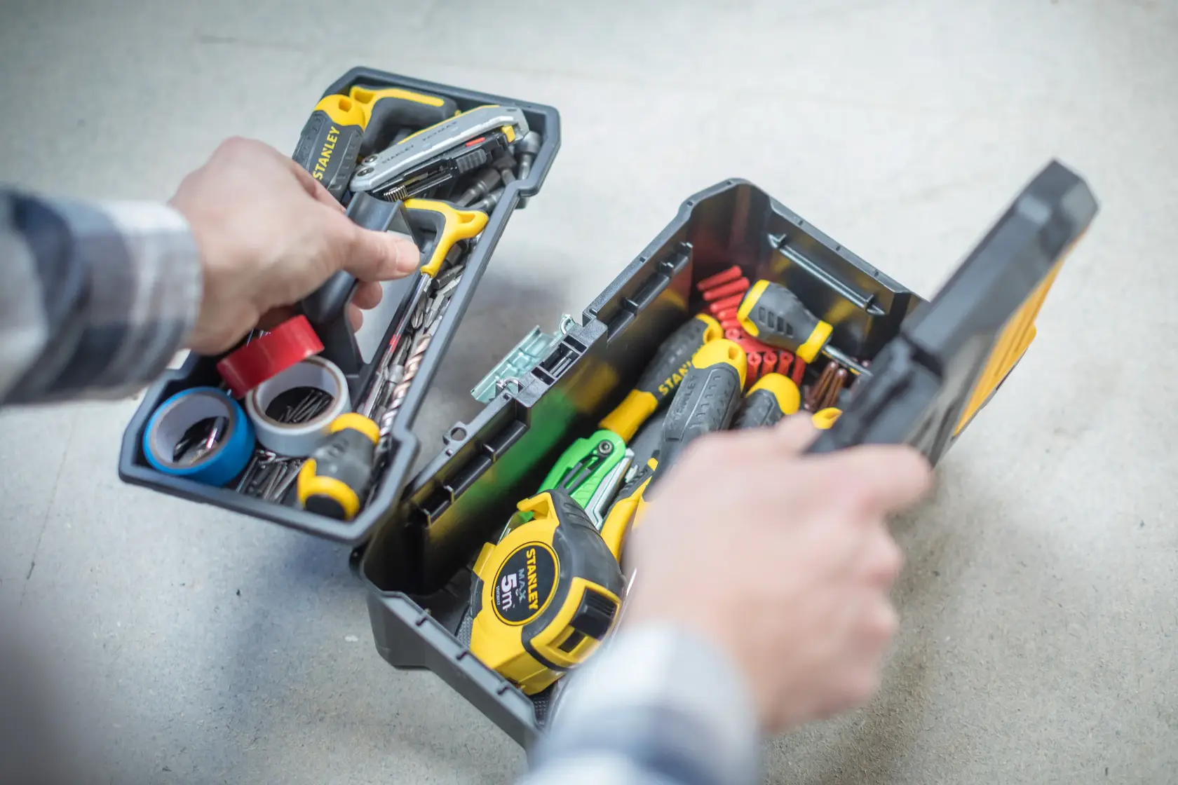 STANLEY toolbox with tools, tape, STST1-75515, STST1-75515-KR, open on gray surface, hands holding tray.