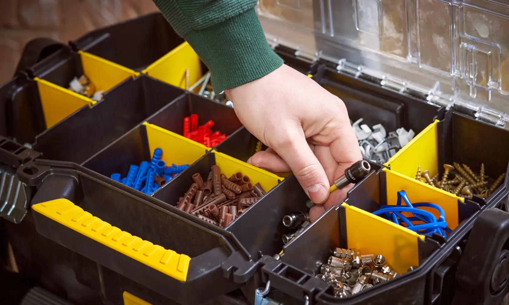 STANLEY STST1-79231 organizer box with yellow dividers, assorted fasteners, close-up with hand.