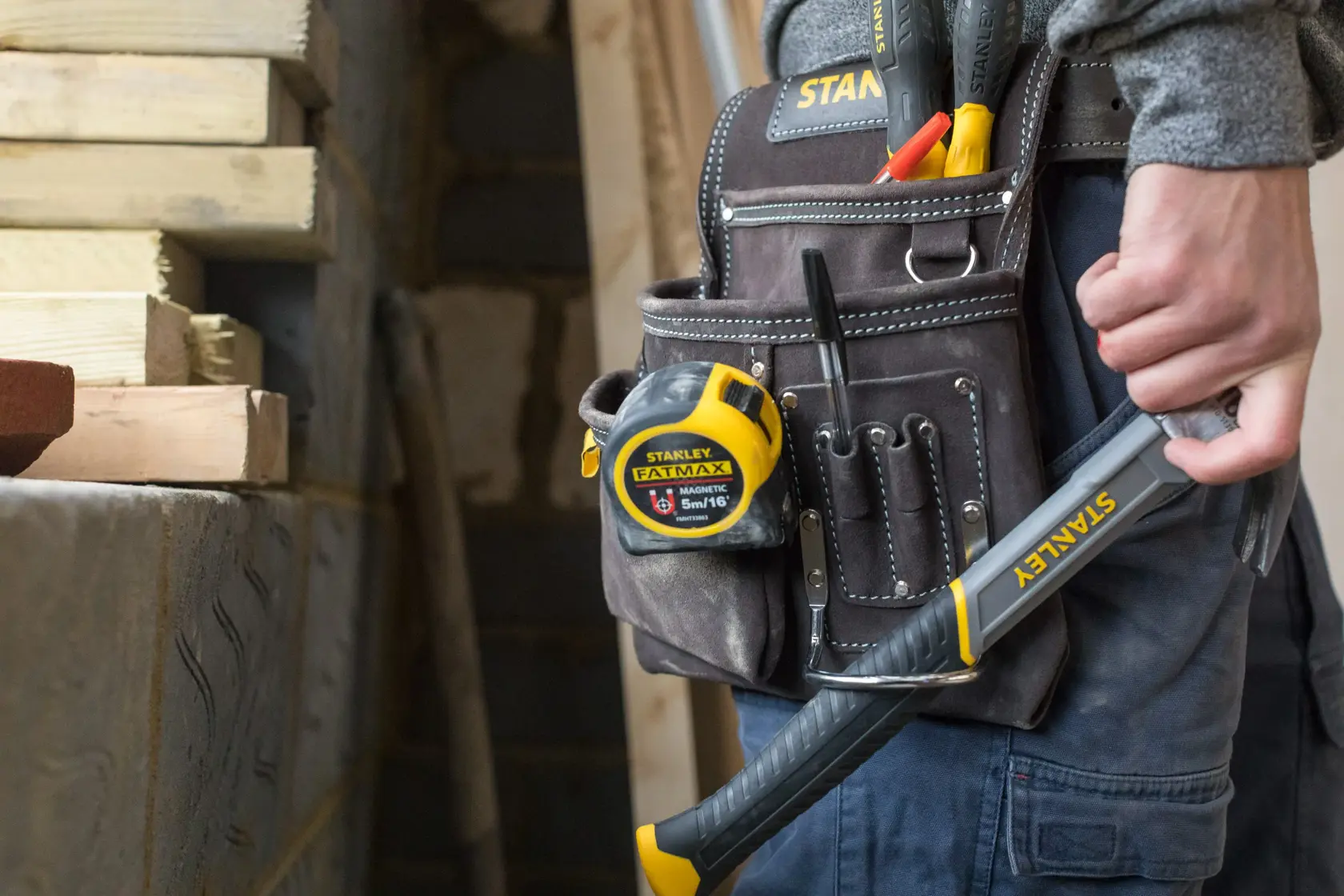 STANLEY STST1-80114 tool belt with tape measure, hand tools, and hammer in use at a construction site.
