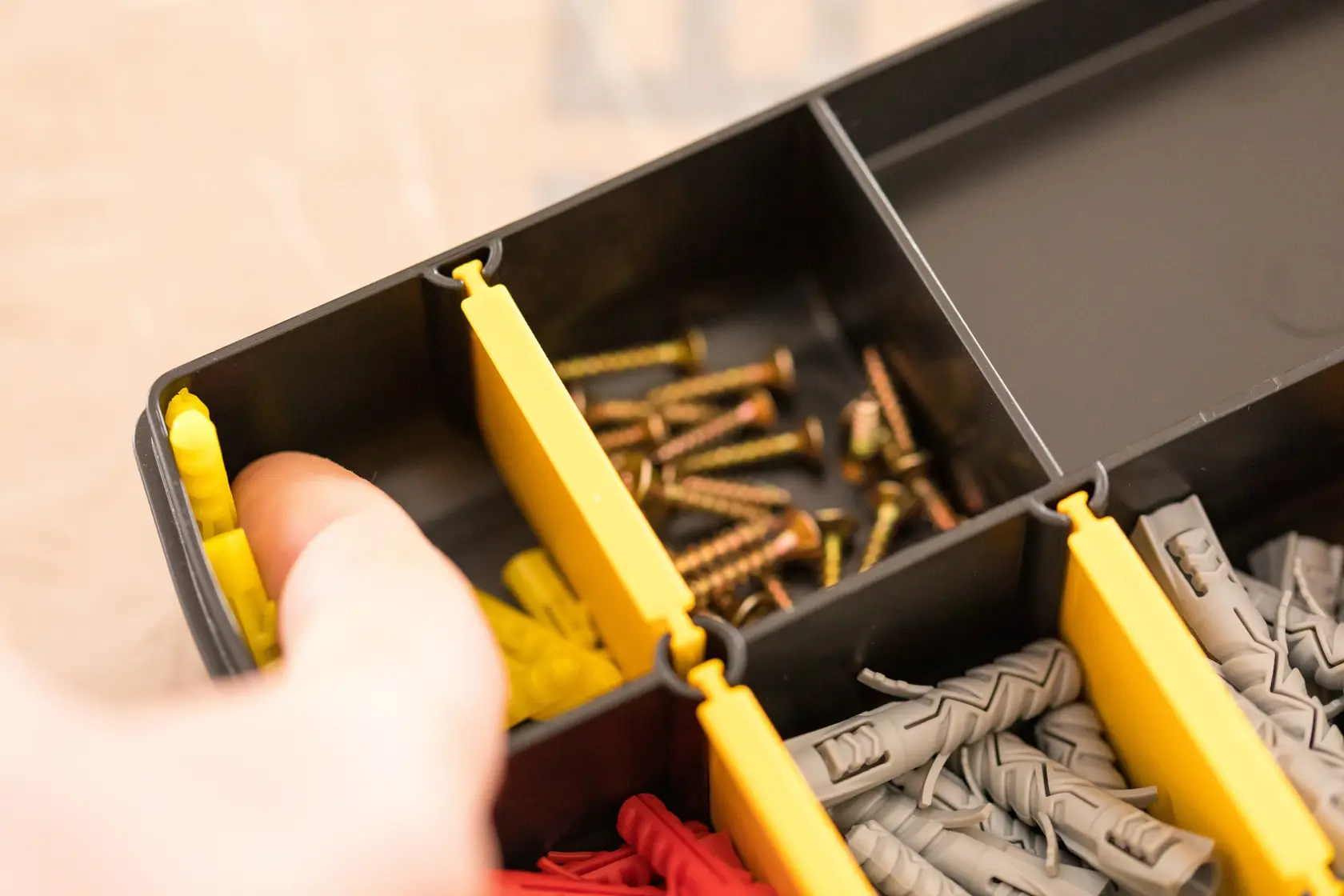 STANLEY STST81680-1 organizer box with yellow dividers, storing screws and wall plugs, close-up angle.
