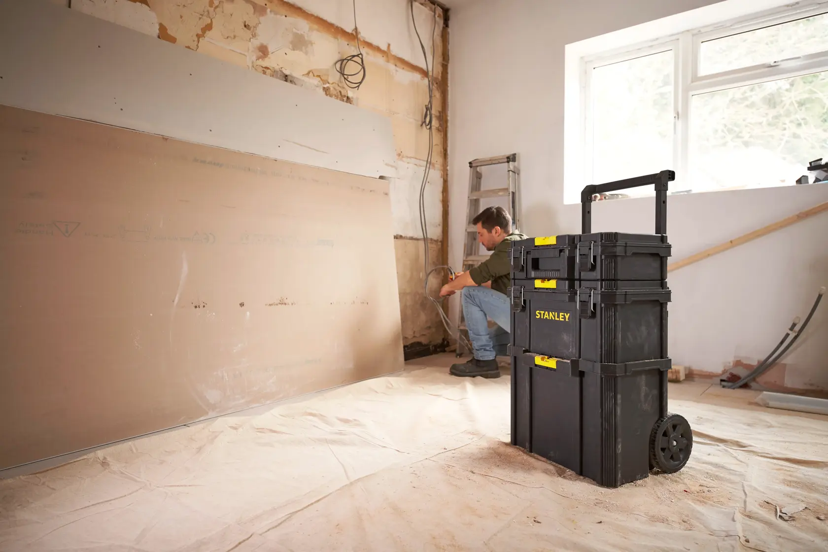 STANLEY STST83319-1 rolling tool chest in a remodel room, black plastic with yellow accents.
