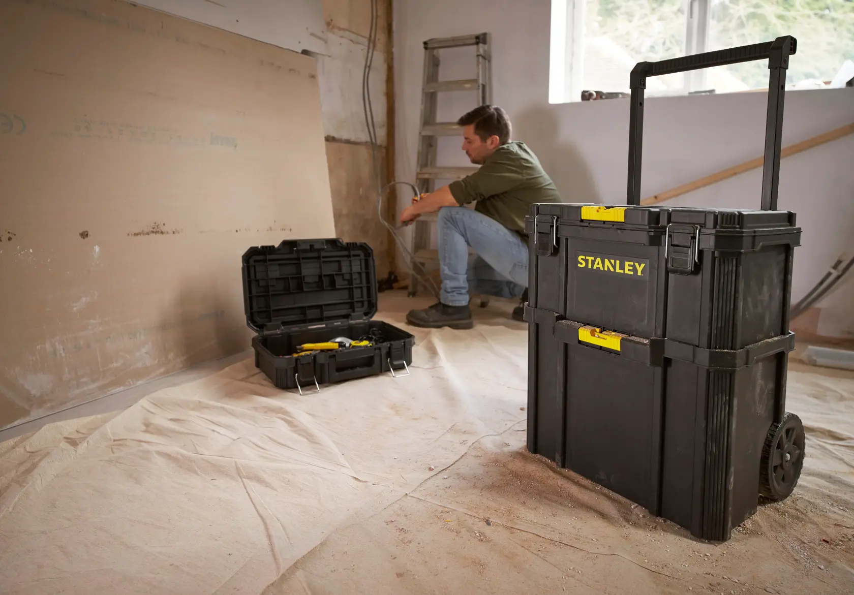 STANLEY STST83319-1 rolling tool chest shown in a workshop with open tool box in background.