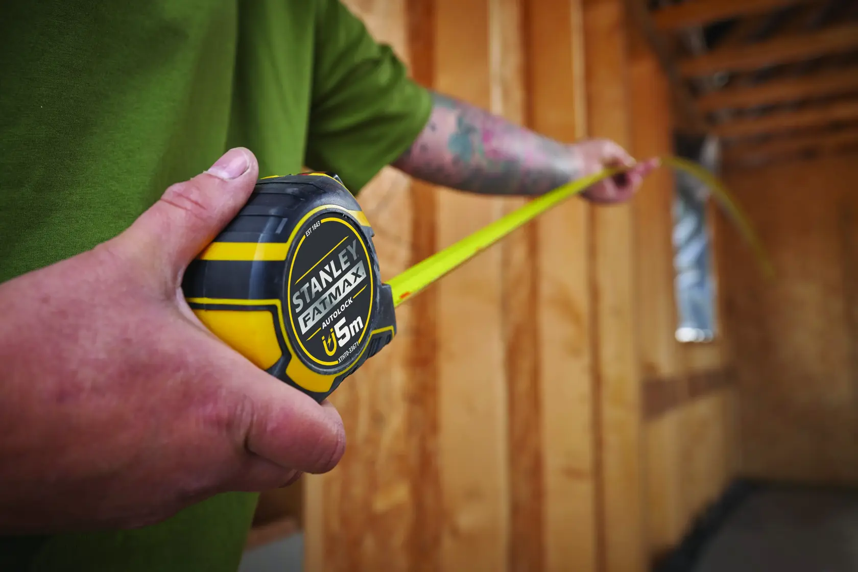 Photo of STANLEY XTHT0-33671 tape measure, black and yellow, being used in a wooden construction interior.