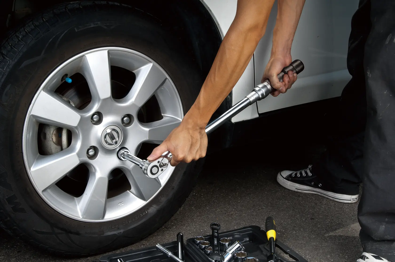STANLEY Torque_wrench photography showing silver torque wrench tightening car wheel lug nuts outdoors.